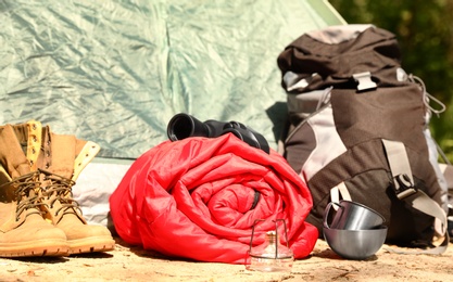 Rolled sleeping bag and other camping gear outdoors on sunny day