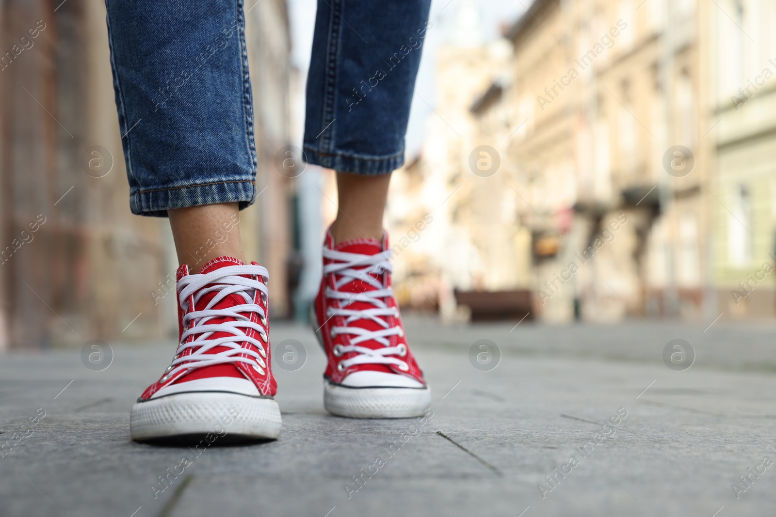 Photo of Woman in stylish sneakers walking on city street, closeup. Space for text