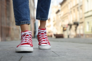 Woman in stylish sneakers walking on city street, closeup. Space for text