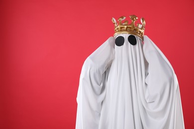 Person in ghost costume and luxurious crown on red background, space for text