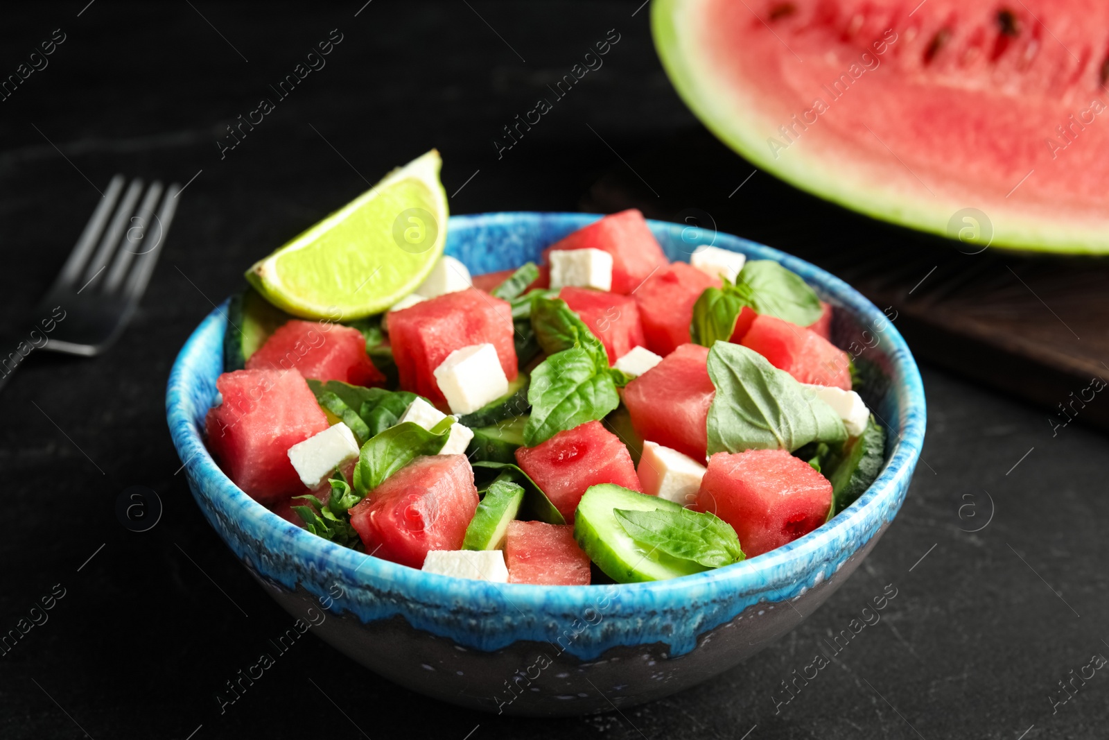 Photo of Delicious salad with watermelon served on black table