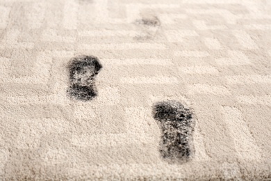 Photo of Trail of muddy footprints on beige carpet