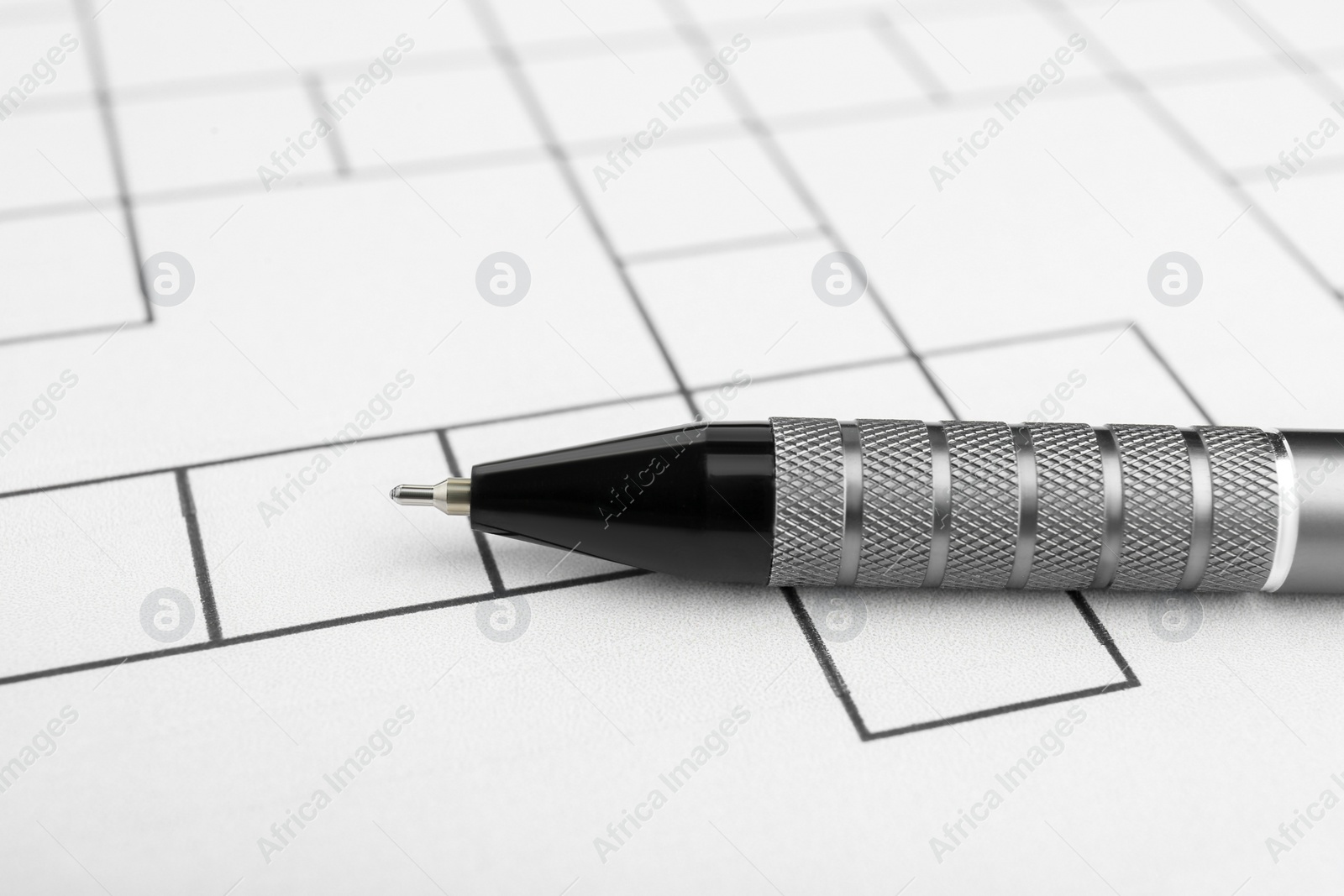 Photo of Pen on blank crossword, closeup. Intellectual entertainment