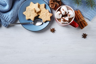 Flat lay composition of tasty cocoa with marshmallows on white wooden table. Space for text