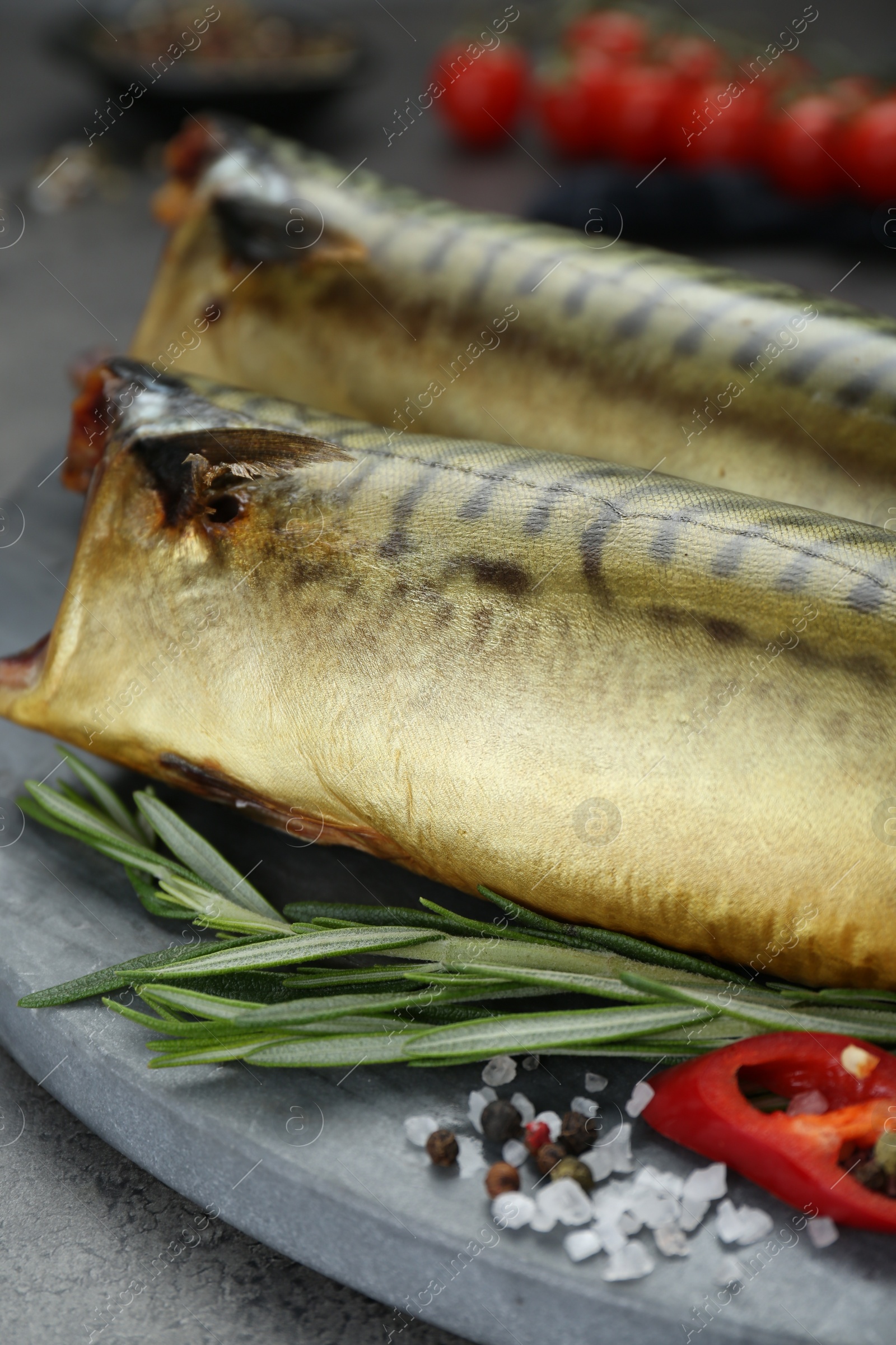 Photo of Delicious smoked mackerels and spices on dark grey table, closeup