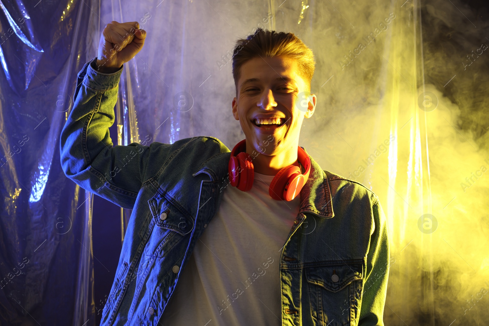 Photo of Young man with headphones in neon lights with smoke effect