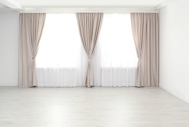Photo of Windows with elegant curtains in empty room