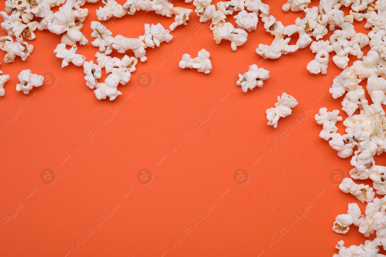 Photo of Tasty popcorn scattered on orange background, space for text