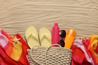 Photo of Flat lay composition with wicker bag and other beach accessories on sand. Space for text