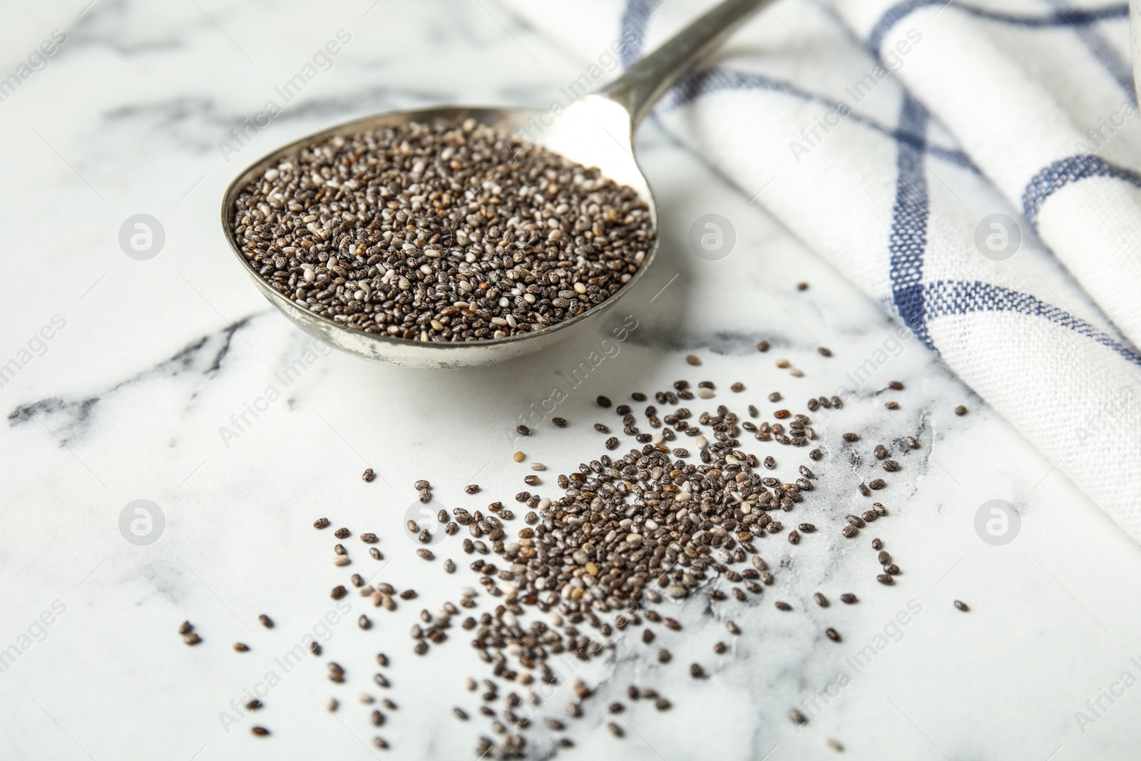 Photo of Spoon with chia seeds on marble table, closeup