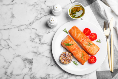 Delicious roasted fish served on white marble table, flat lay. Space for text