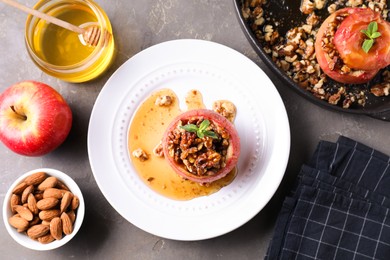 Tasty baked apple with nuts, honey and mint on gray table, flat lay