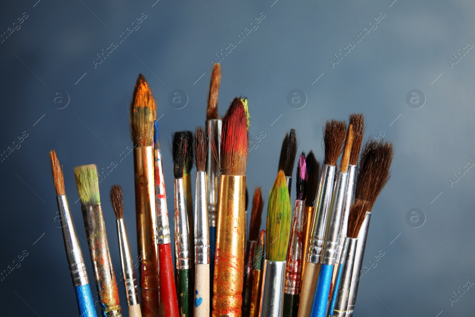 Photo of Different paint brushes on color background, closeup
