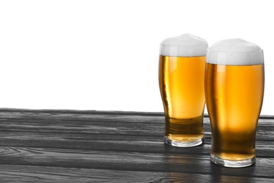 Glasses of tasty beer on black wooden table against white background. Space for text