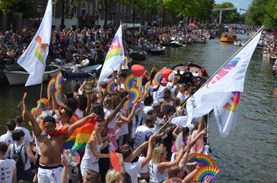 Photo of AMSTERDAM, NETHERLANDS - AUGUST 06, 2022: Many people in boats at LGBT pride parade on river