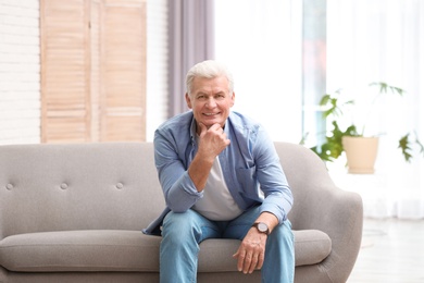 Portrait of handsome mature man on sofa indoors