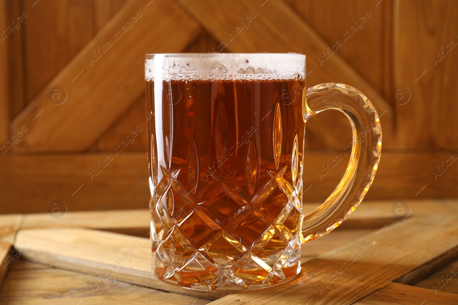 Photo of Mug with fresh beer on wooden crate, closeup