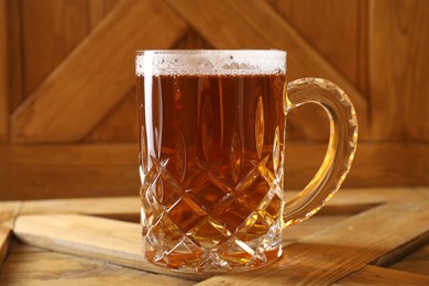 Mug with fresh beer on wooden crate, closeup