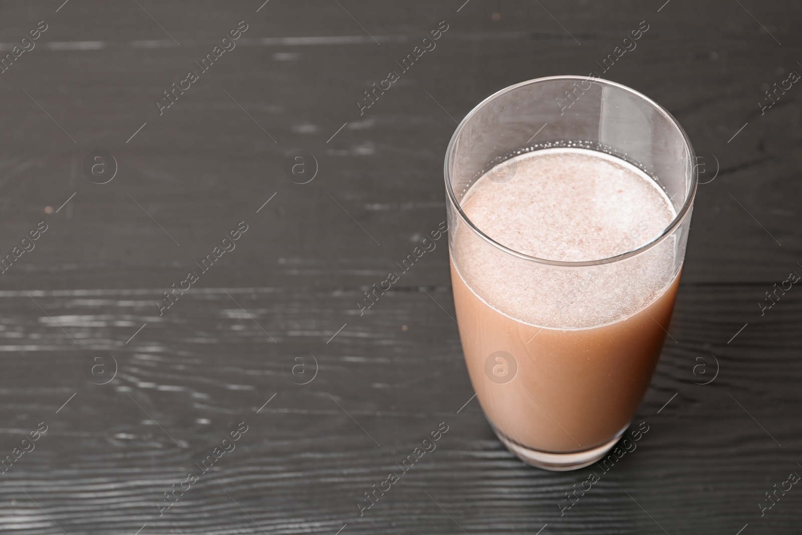 Photo of Glass of chocolate protein shake on black wooden background. Space for text