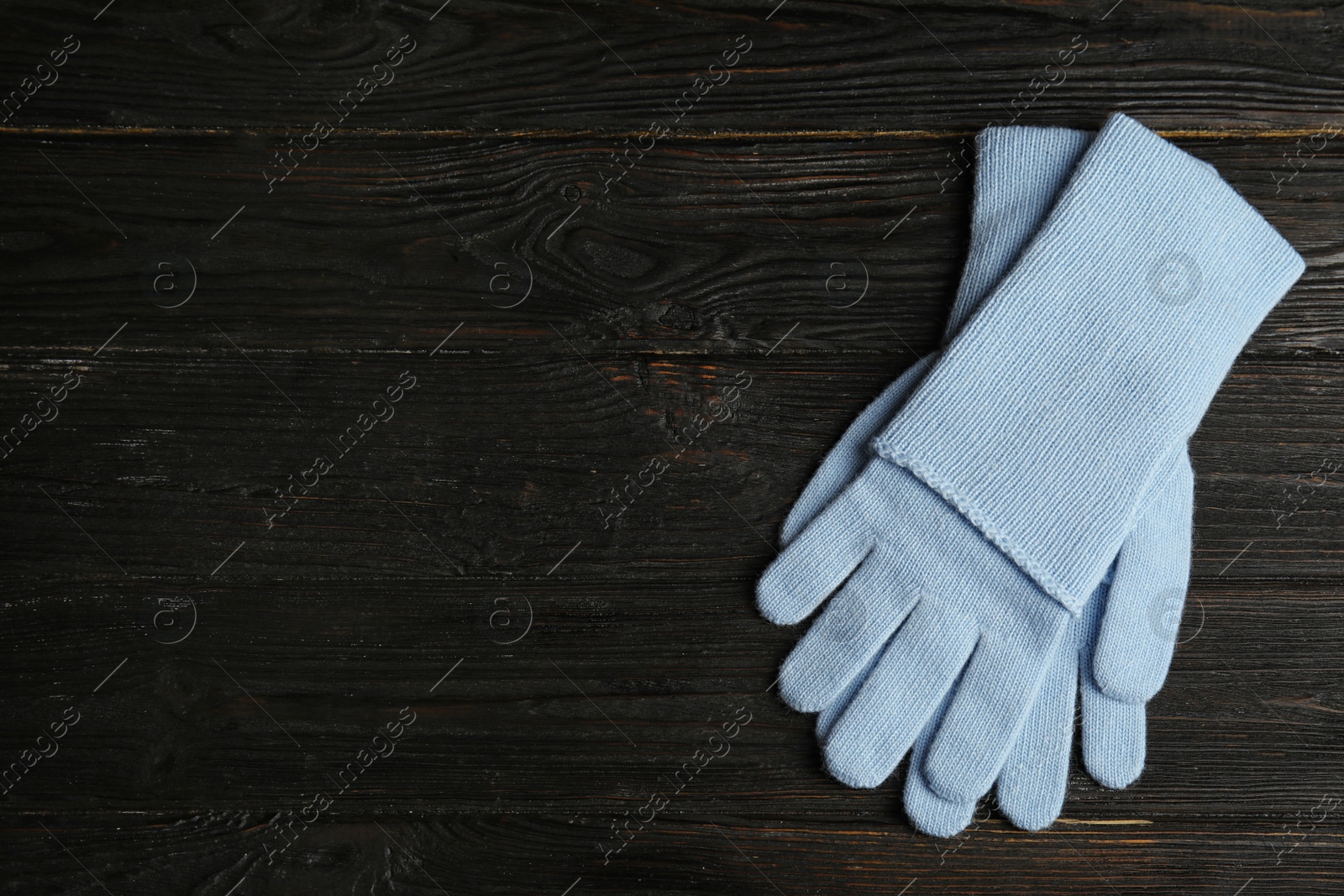 Photo of Stylish blue gloves on dark wooden background, top view with space for text. Autumn clothes