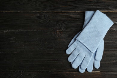 Photo of Stylish blue gloves on dark wooden background, top view with space for text. Autumn clothes