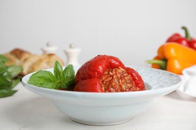 Photo of Delicious stuffed pepper with basil in bowl on white table, space for text