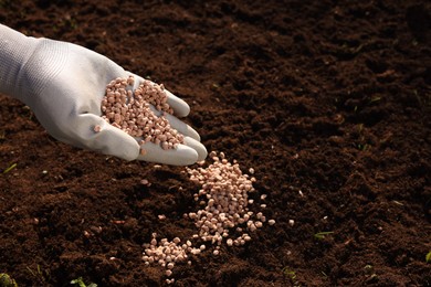 Photo of Man fertilizing soil, closeup. Space for text