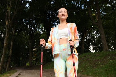 Photo of Young woman practicing Nordic walking with poles on steps outdoors, low angle view