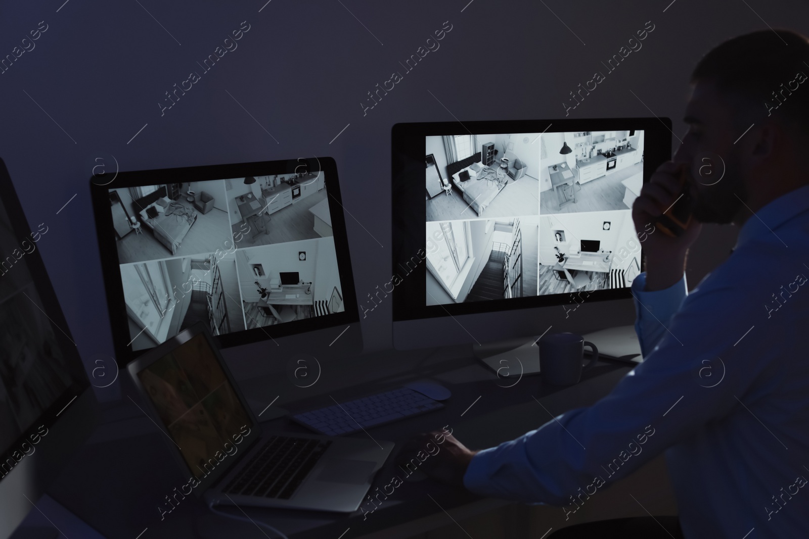 Photo of Male security guard with portable transmitter monitoring home cameras indoors at night