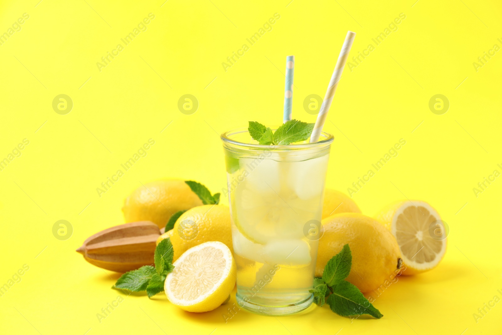 Photo of Natural freshly made lemonade with squeezer on yellow background. Summer refreshing drink