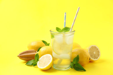 Photo of Natural freshly made lemonade with squeezer on yellow background. Summer refreshing drink