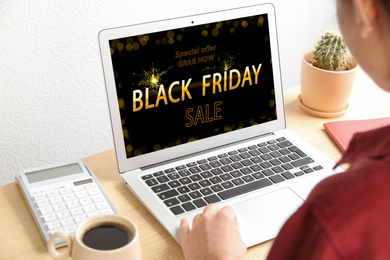 Black Friday. Woman shopping online using laptop at table, closeup