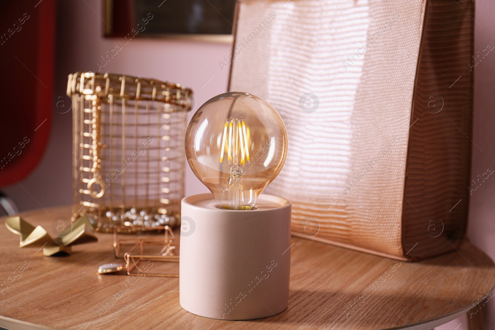 Photo of Modern night lamp, stylish bag and decor on wooden table indoors