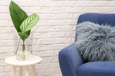 Tropical leaves in glass vase on table indoors. Idea for modern stylish interior