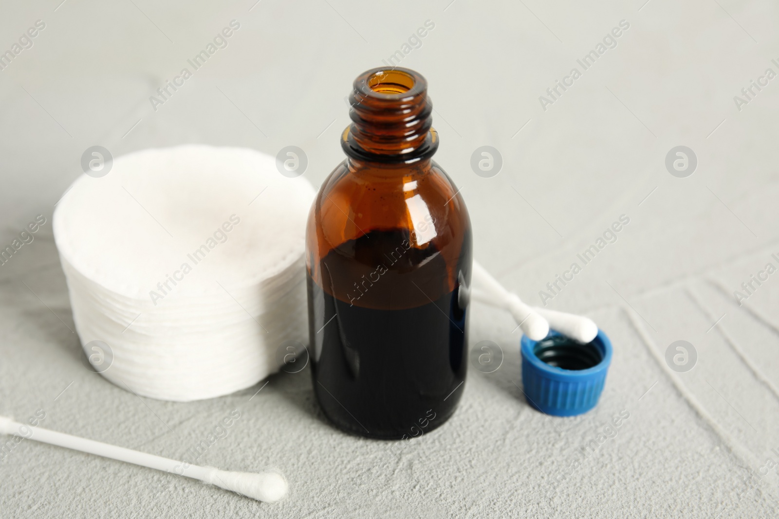 Photo of Bottle of medical iodine, cotton pads and buds on grey table