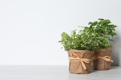 Photo of Different aromatic potted herbs on white wooden table. Space for text