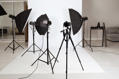 Photo of Tripod with camera and professional lighting equipment in photo studio