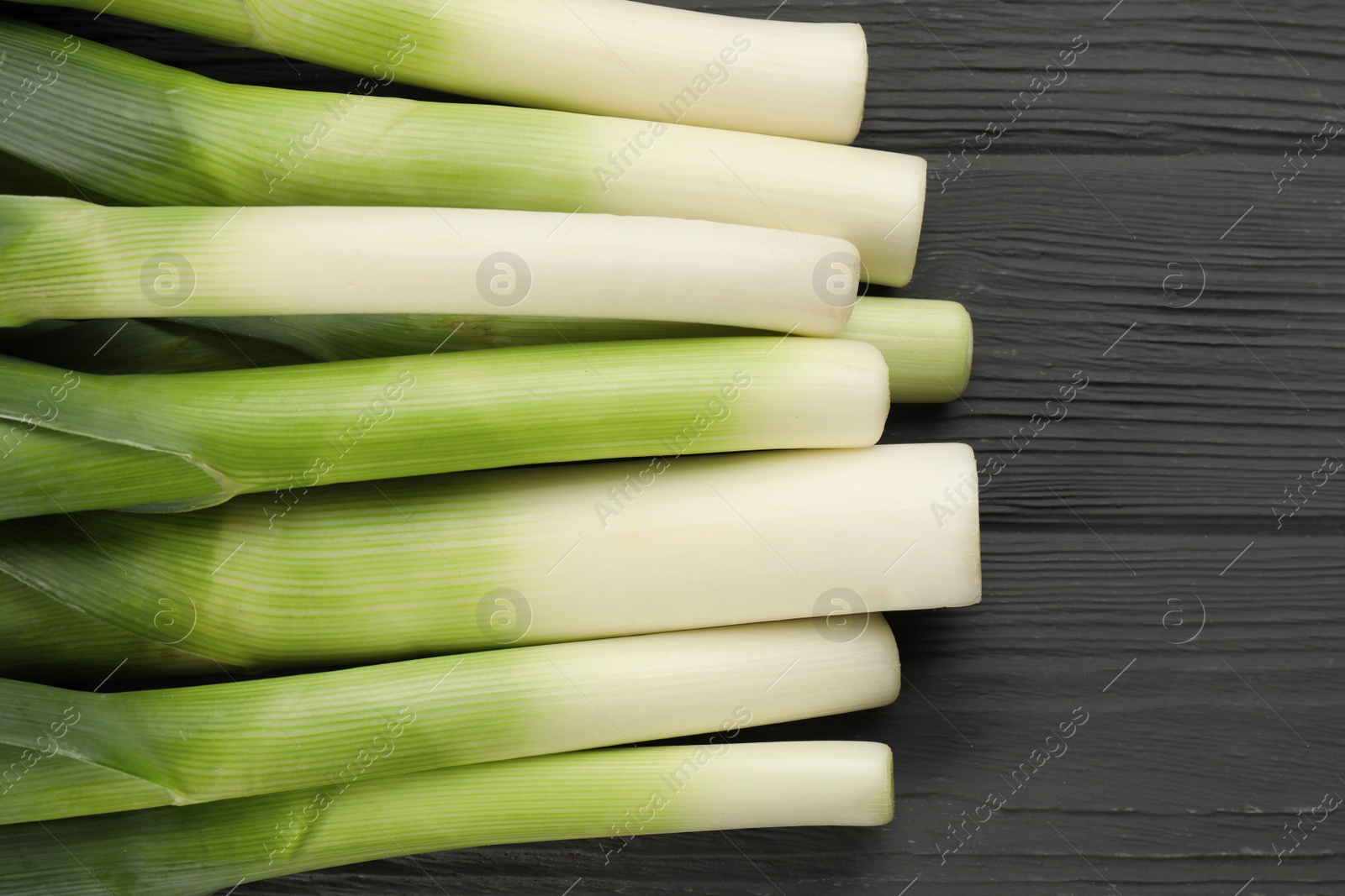 Photo of Fresh raw leeks on grey wooden table, flat lay