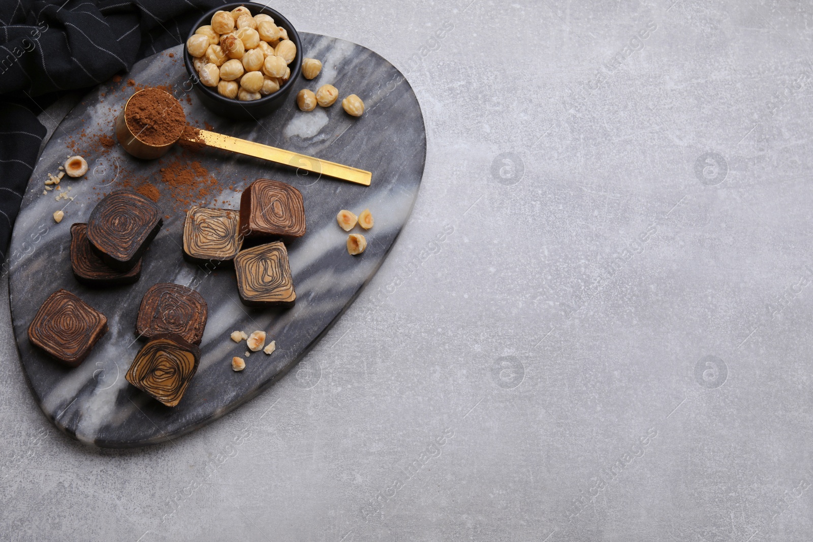 Photo of Flat lay composition with tasty chocolate candies and nuts on light grey table. Space for text