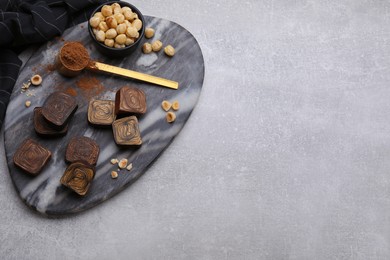 Photo of Flat lay composition with tasty chocolate candies and nuts on light grey table. Space for text