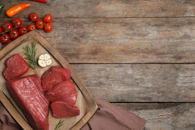 Photo of Flat lay composition with fresh raw meat, products and space for text on wooden background