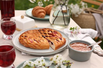 Photo of Stylish table setting with beautiful spring flowers, fruit drink and pie in garden