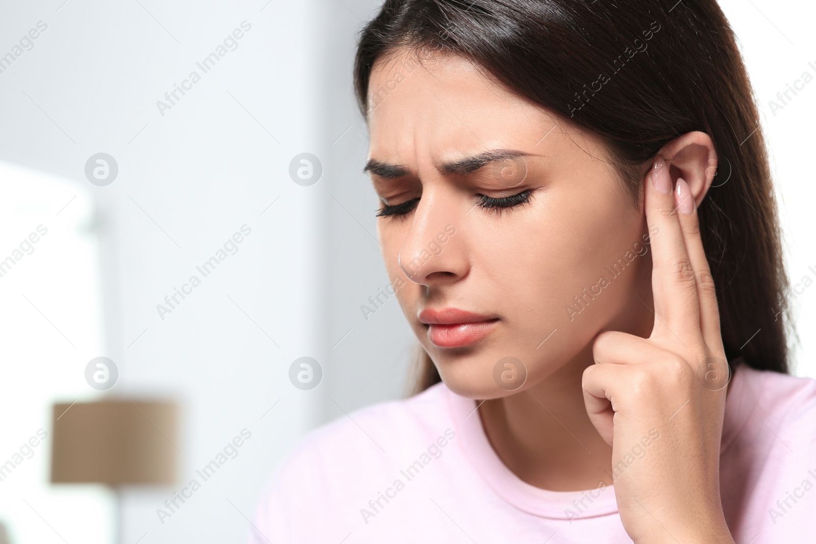 Photo of Young woman suffering from ear pain indoors, closeup. Space for text