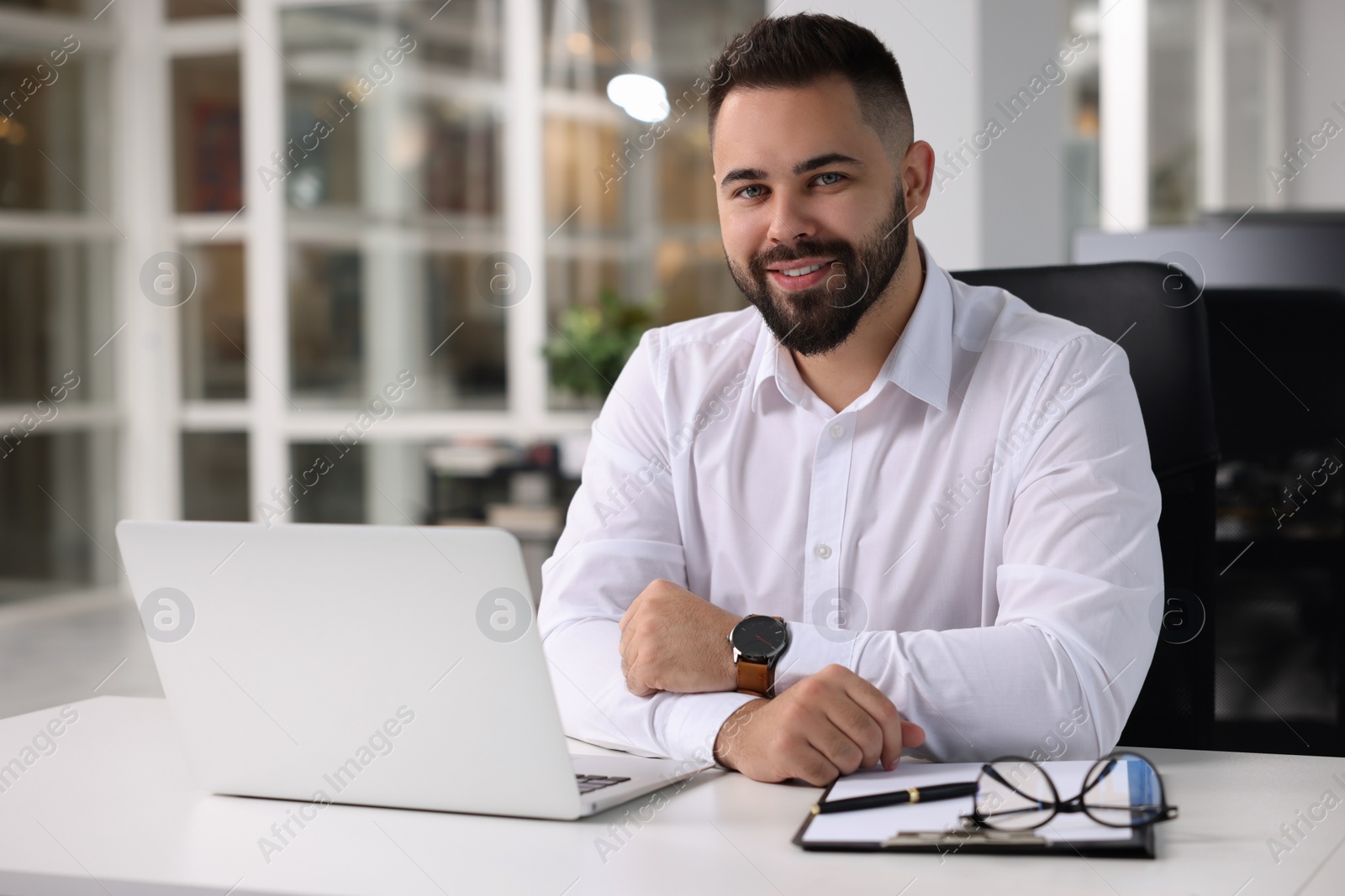 Photo of Portrait of smiling man at table in office. Lawyer, businessman, accountant or manager