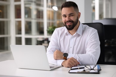 Photo of Portrait of smiling man at table in office. Lawyer, businessman, accountant or manager