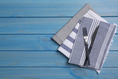 Photo of Different kitchen towels with cutlery on blue wooden table. Space for text