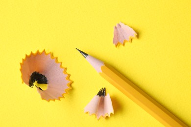 Graphite pencil and shavings on yellow background, top view. Macro photo