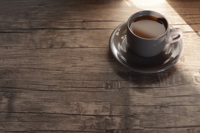 Cup of morning coffee on wooden table, space for text