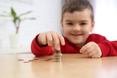 Cute little boy with coins at home, closeup. Counting money