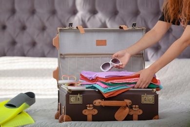 Woman packing suitcase for journey at home